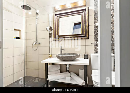 Modernes Interieur Badezimmer mit Waschbecken und Spiegel, Glas begehbare Dusche mit Marmor Fliesen Surround Stockfoto