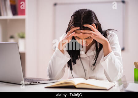 Junger Arzt ist müde. Sie hat Kopfschmerzen in Ihrem Büro. Stockfoto