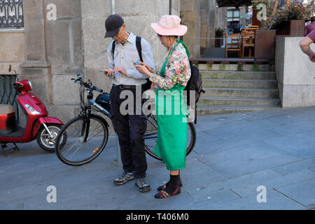 Eine ältere japanisches Paar Navigieren in den Straßen von Porto mit Karten auf ihre Mobiltelefone in einer Straße in Portugal Europa KATHY DEWITT Stockfoto