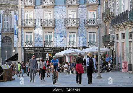 Radfahrer reiten Fahrrad entlang der Rua das Flores Vergangenheit Gebäude mit blauen azulejos Fliesen, Restaurant und Touristen auf der Straße Porto Portugal Europa KATHY DEWITT Stockfoto