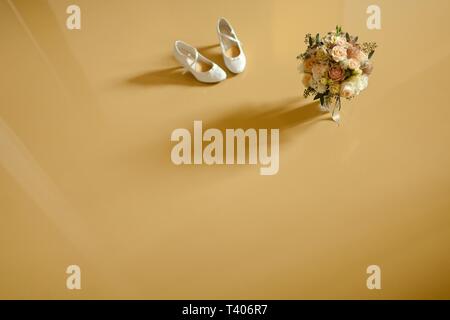 Bouquet und Hochzeit Schuhe auf gelb Stock von oben Blick gefangen und werfen Schatten. Stockfoto