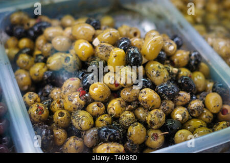 Stapel der Oliven im Lebensmittelmarkt closeup - Oliven mit Kräutern und Gewürzen Stockfoto