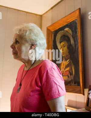Senior afrikanische amerikanische Frau in Ihrem Hause vor einem Gemälde von sich selbst als eine jüngere Frau Stockfoto