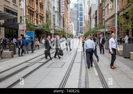 Mitarbeiter im Büro zu Fuß über Light Rail Track im Stadtzentrum von Sydney, Australien Stockfoto