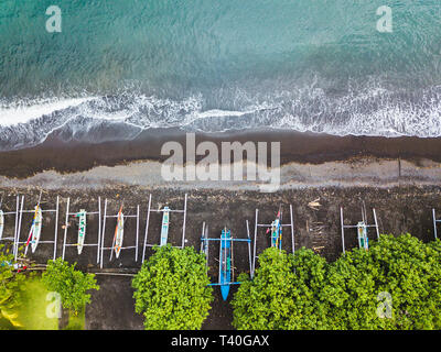Von oben nach unten Luftbild von traditionellen indonesischen Fischerbooten genannt jukung auf schwarzem Sand Strand. In Amed, Bali, Indonesien. Stockfoto