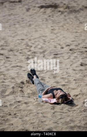 Eine Dame Sunbathes am Strand in Bournemouth, Dorset. Stockfoto