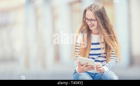 Porträt eines lächelnden schönen teenage Mädchen mit Zahnspangen. Junge Schulmädchen mit Schultasche und Tablet Gerät. Stockfoto