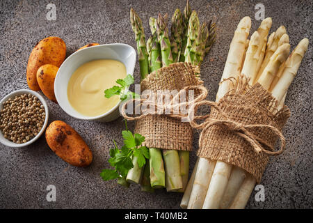 Zutaten für ein gourmet Spargel Vorspeise mit Bündeln von frischen weißen und grünen Stangen, Mayonnaise, neuen Kartoffeln und Pfefferkörner Stockfoto