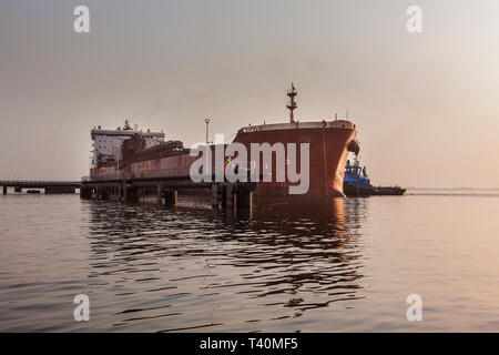 Port Operations für den Transport von Eisenerz. Schlepper Halten und Bewegen transhipper Schiffes Dock an Layby Jetty vor Wechsel zu laden Jetty Stockfoto