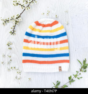 Feder Strickmütze auf weißem Hintergrund mit Blumen und Zweige Stockfoto