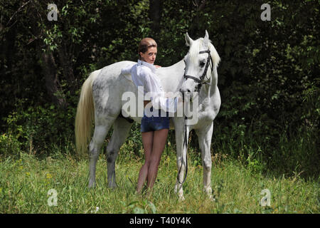 Schöne cowgirl bareback Spaziergänge mit Pferd im Wald Lichtung bei Sonnenuntergang Stockfoto