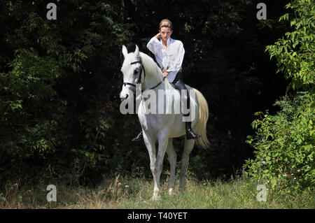 Schönes Modell cowgirl Bareback ihr Pferd im Wald Lichtung bei Sonnenuntergang Stockfoto