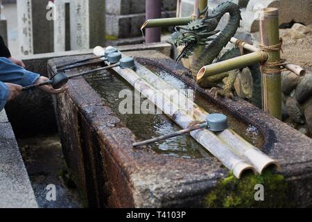 Nahaufnahme einer Person ihre Hände waschen mit Wasser für die Reinigung gemeint, in Nara, Japan. Stockfoto