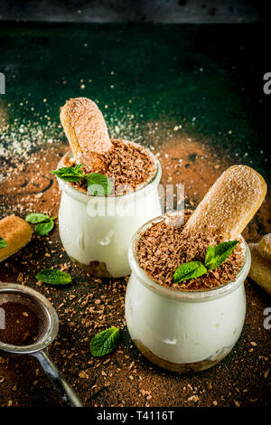 Hausgemachte italienische Dessert Tiramisu in kleinen Portionen Gläser, dunklen konkreten Hintergrund Kopie Raum Stockfoto