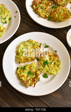 Gemüse Pfannkuchen. Zucchini Krapfen auf weißen Platte über Holz- Hintergrund. Vegetarisches Essen. Stockfoto