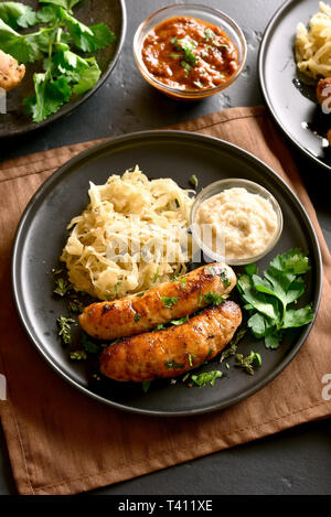 Leckere hausgemachte Wurst mit Schmorkohl und Meerrettich auf die Platte über der schwarzen Stein Tabelle Stockfoto