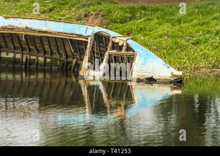 In der Nähe der Hälfte versenkte Boot Wrack am Ufer eines Flusses Stockfoto