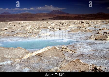 Blick auf den blau schimmernden Salz Wasser Pfütze in rauen kargen getrocknet Gelände - Salar (Salzsee) in der Nähe von San Pedro de Atacama Stockfoto