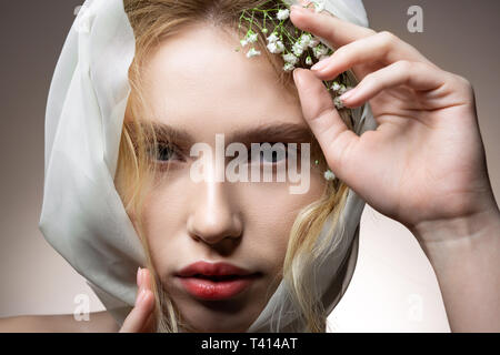 Modell mit dicken Augenbrauen mit weißen Blumen im Haar posing Stockfoto