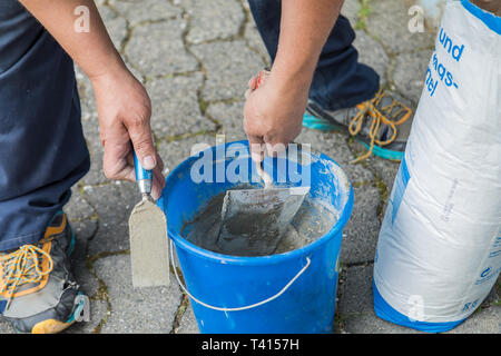 Zwei Hände mit Maurer Kelle, Mörtel vorbereiten. Stockfoto