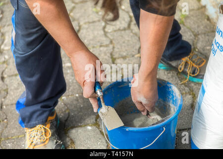 Zwei Hände mit Maurer Kelle, Mörtel vorbereiten. Stockfoto