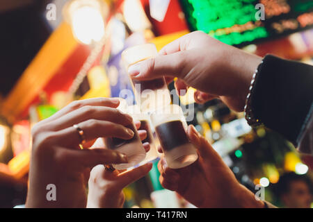 Männliche Hände jubeln mit Brille der Schuß oder Likör. Freunde trinken erschossen oder Likör und Prost. Männliche Hände jubeln mit Alkohol auf unscharfen bar Hintergrund Stockfoto