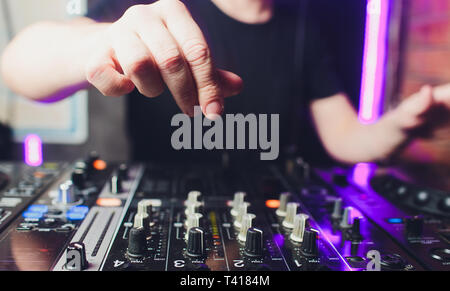 Nahaufnahme der Hände der männlichen disc jockey Mischen Musik auf seinem Deck mit seinen Händen über die Schallplatte auf den Plattenteller und die Kontrolle balanciert Stockfoto