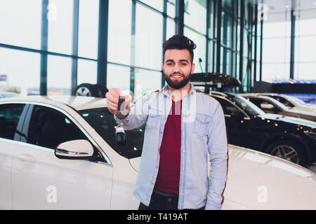 Glückliche Käufer holding Schlüssel in der Nähe des Auto vor der modernen avtosalon Gebäude. Stockfoto