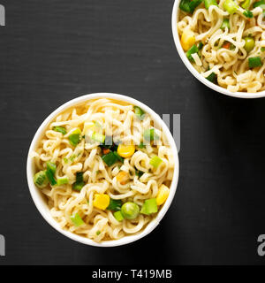 Leckere instant Ramen Nudeln mit Rindfleisch Aroma in Pappbechern über schwarzen Oberfläche. Flach, von oben, Overhead. Close-up. Stockfoto