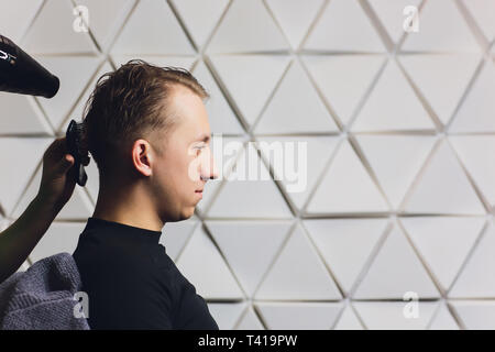 Weibliche Friseur die Haare trocknen Ihre männlichen Kunden in ihrem Friseursalon. Stockfoto