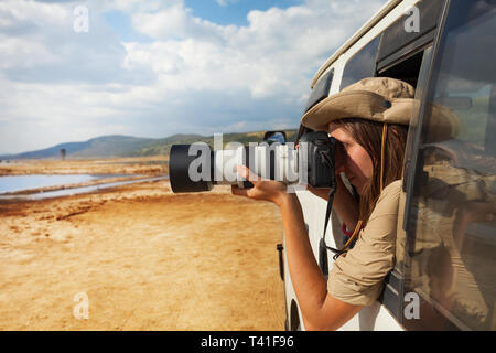 Seitenansicht Porträt der jungen Frau unter Foto des kenianischen Lake Nakuru aus dem geöffneten Fenster der Safari Jeep Stockfoto