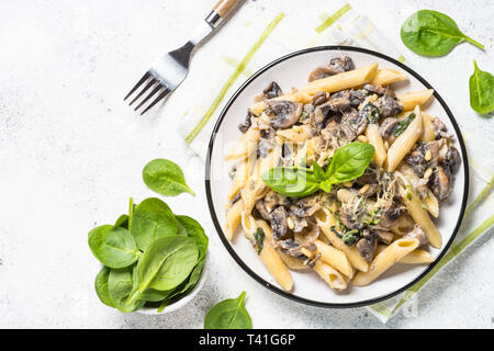 Pasta mit Pilzen und Spinat auf Weiß. Stockfoto