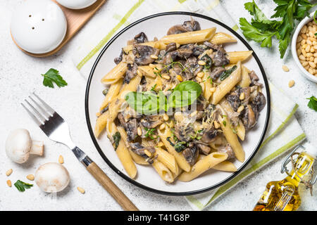 Pasta mit Pilzen und Spinat auf Weiß. Stockfoto