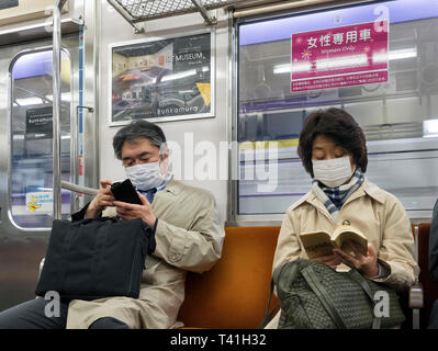 Fahrgäste, die auf der Tokyo Metro tragen Gesichtsmasken, eine gemeinsame Sicht in Tokio, Japan. Stockfoto