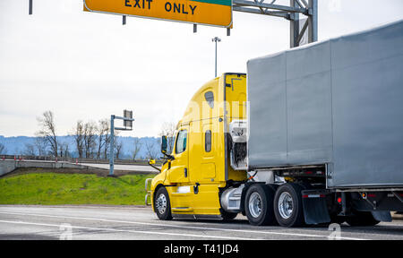 Leuchtend gelbe leistungsstarke Fernverkehr Güterverkehr Big Rig Motorhaube Semi Truck Transport von Gütern in semi Trailer mit schwarz gummiertem Fab abgedeckt Stockfoto