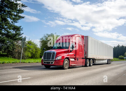 Red Big Rig gängigen professionellen zuverlässige Motorhaube Long Haul Semi Truck Transport von kommerziellen Ladung in trockenen van Auflieger bewegen auf dem geraden wid Stockfoto