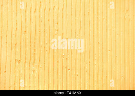 Detailansicht der Wand mit einem dekorativen gelben Putz vertikale Linien und Streifen. Strukturierte Betonwand mit als Textur oder Hintergrund. Einfügen Stockfoto