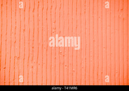 Detailansicht der Wand mit einem dekorativen Coral farbigen Putz vertikale Linien und Streifen. Strukturierte Betonwand mit als Textur oder Hintergrund. Trendy Stockfoto