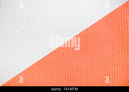 Detailansicht der Wand mit einem dekorativen Putz vertikale Linien und Streifen. Trendy zweifarbig Hintergrund Textur. Texturierte weiß und Coral Betonwand. Stockfoto