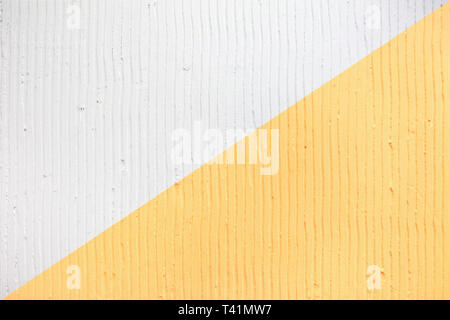 Detailansicht der Wand mit einem dekorativen Putz vertikale Linien und Streifen. Trendy zweifarbig Hintergrund Textur. Strukturierte weiße und gelbe Betonwand Stockfoto