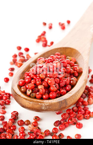 Pink oder Rosa brasilianischen roter Pfeffer (Schinus terebinthifolius) Löffel aus Holz mit weißem Hintergrund Stockfoto