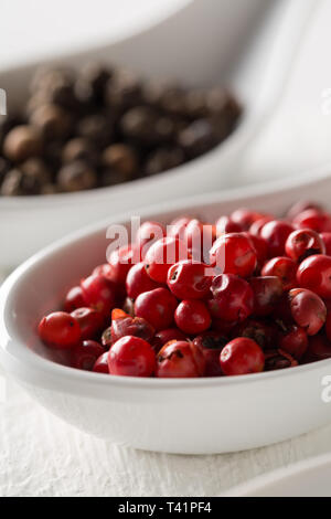 Pink oder Rosa brasilianischen roter Pfeffer (Schinus terebinthifolius) in Weiß Löffel auf weiße Holztisch Hintergrund - selektive Fokus Stockfoto