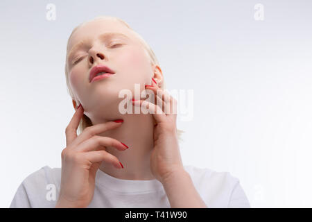 Natürliches Make up. Schöne junge Modell mit natürlichen Make-up-Gefühl freudiger Während posiert in der Nähe von weißen Wand Stockfoto