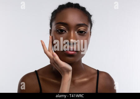 Die weiße Hand berühren Gesicht der Dunkelhäutige schöne Frau Stockfoto