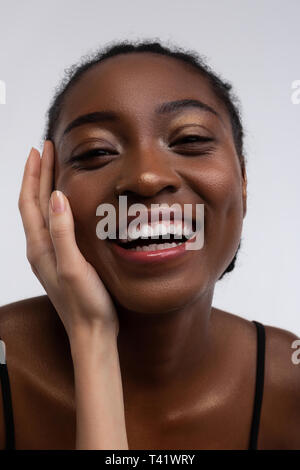 Afrikaner - Frau lächelnd, während weiße Hand ihr Gesicht zu berühren Stockfoto