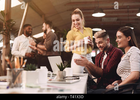 Kolleginnen und Kollegen, die am Projekt, mit Laptop am Arbeitsplatz Stockfoto