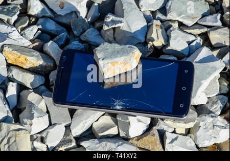 Frustriert Telefon auf den Felsen. Glas zerbrochen auf Felsen auf einem Smartphone. Smartphone fiel und stürzte ab. Stockfoto