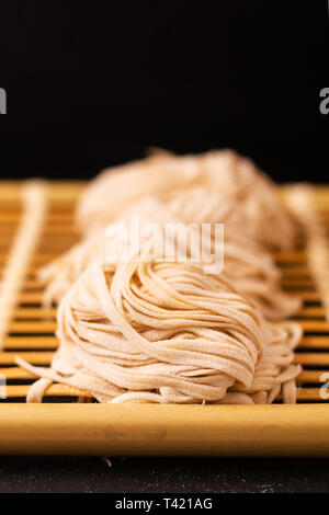 Asiatische Lebensmittel Konzept hausgemachte uncook orientalische Eiernudeln auf Bambus tablett mit Kopie Raum Stockfoto
