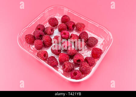 Viel reifer Himbeeren in einer offenen, Kunststoff paket auf einem rosa Hintergrund. Stockfoto