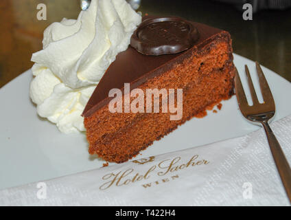 Ein Stück Sachertorte und Schlagsahne sind auf einer Platte mit einer Serviette mit der Aufschrift Hotel Sacher Stockfoto